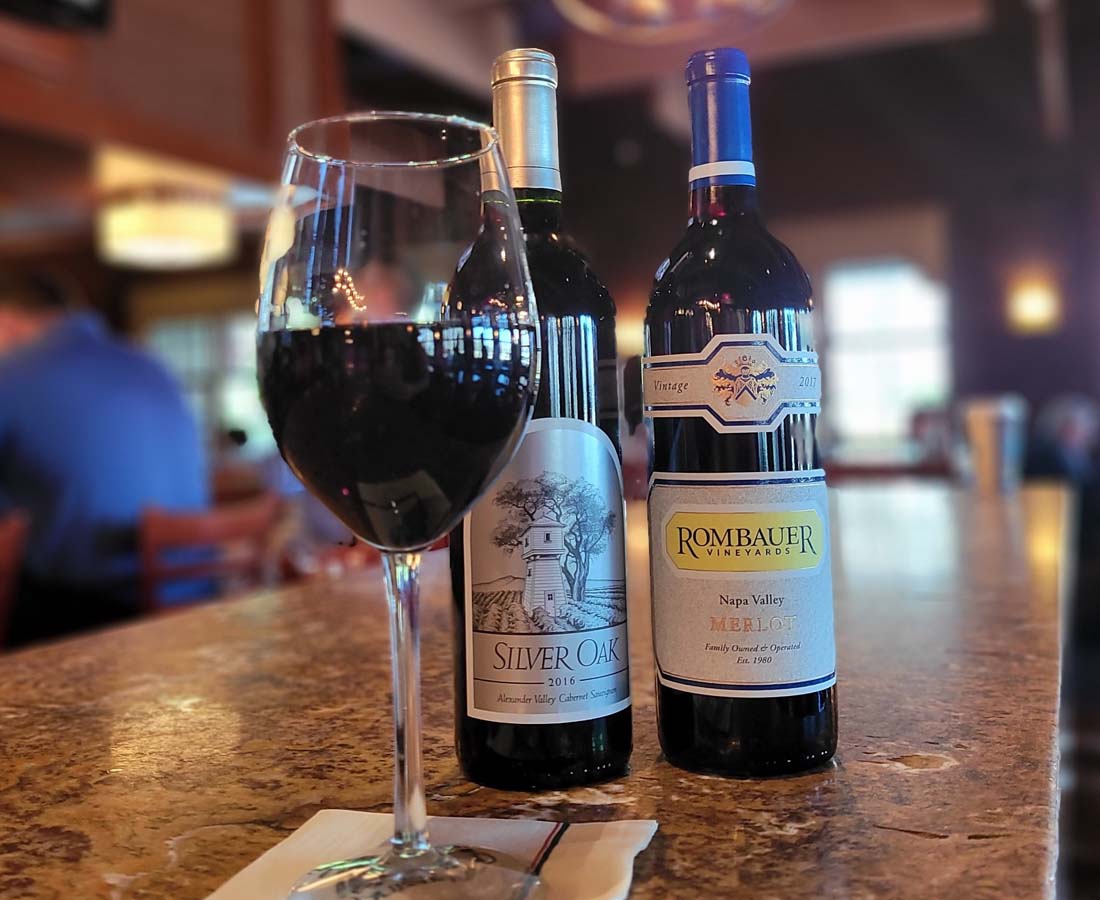 glass of wine and 2 wine bottles